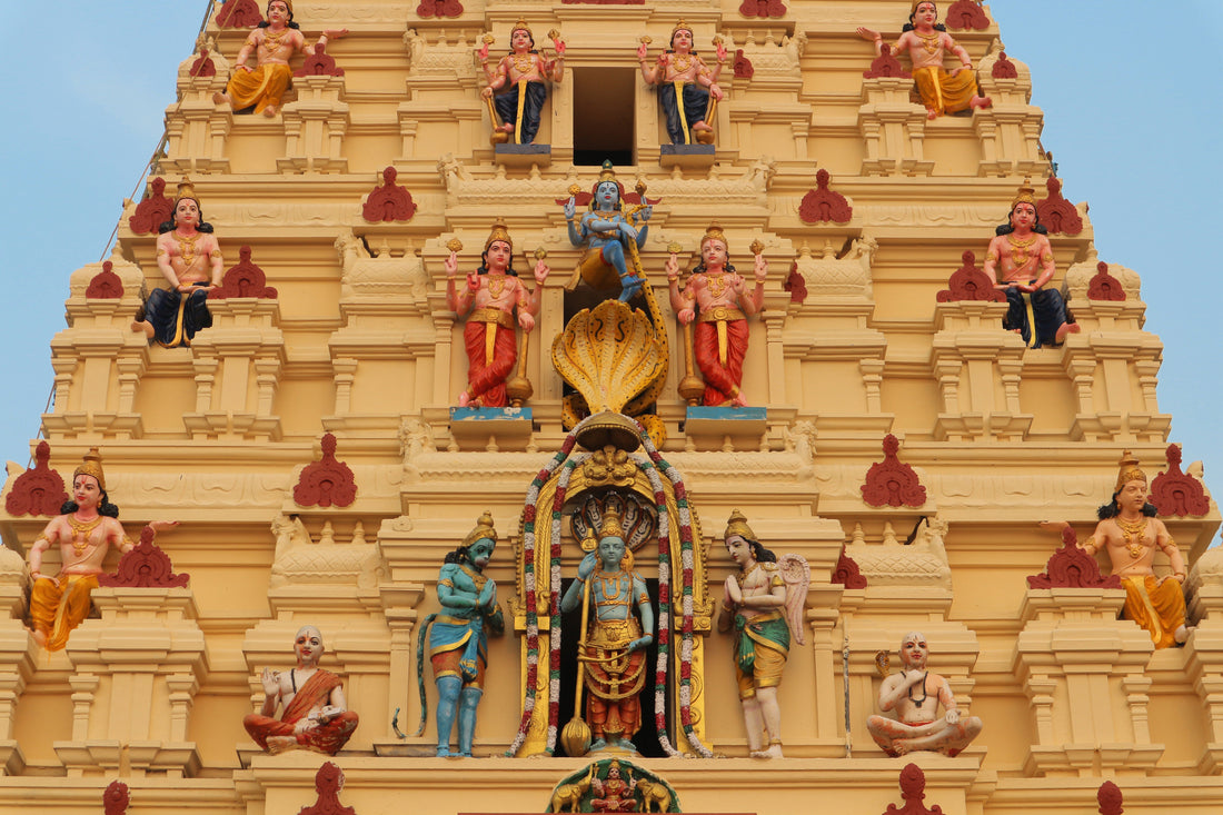 Detailed yellow Hindu temple gopuram with colorful deity sculptures